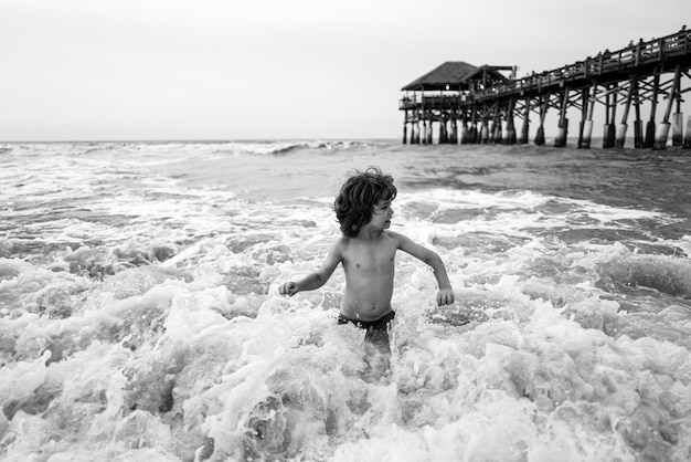 Gelukkig kind spelen in de zee bij zonsondergang kind spelen in de buitenlucht springen in het water op zomervakantie