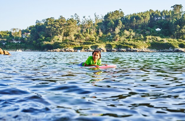 Gelukkig kind spelen in de zee met bodyboard. Kind plezier buitenshuis. Concept van zomervakantie en gezonde levensstijl.