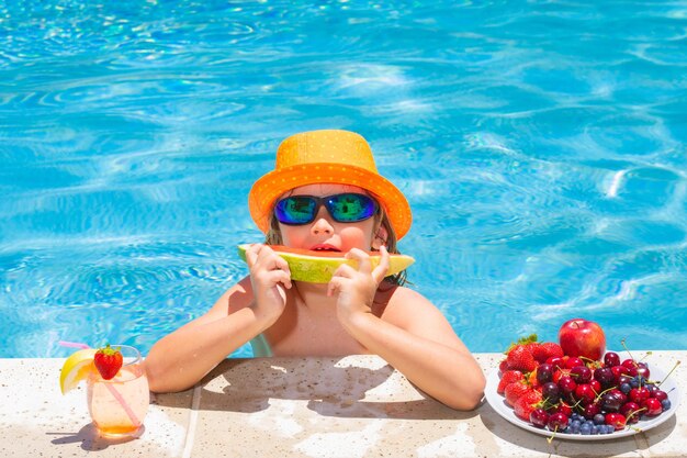 Gelukkig kind spelen in het zwembad Zomervakantie voor kinderen Zomerfruit voor kinderen Kleine jongen jongen ontspannen in een zwembad met plezier tijdens de zomervakantie