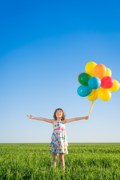 Gelukkig kind spelen met heldere veelkleurige ballonnen buiten