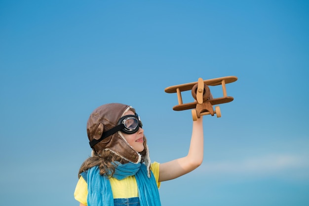Gelukkig kind spelen met speelgoed vliegtuig buitenshuis Kind plezier tegen zomer hemelachtergrond Reizen en verbeelding concept