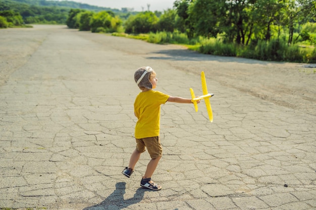 Gelukkig kind spelen met speelgoed vliegtuig tegen oude landingsbaan achtergrond Reizen met kinderen concept