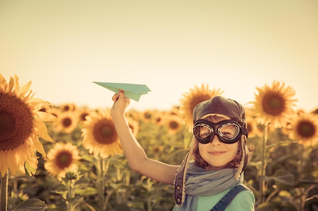 Gelukkig kind spelen met speelgoed vliegtuig tegen zomer hemelachtergrond Reizen en vakantie concept Retro toned