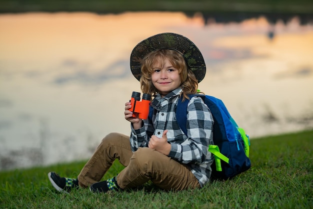 Gelukkig kind spelen met verrekijker Verkennen en avontuur Kind jongen met rugzakken natuur en milieu verkennen Outdoor vrijetijdsbesteding voor kinderen Zomerreis voor toerist