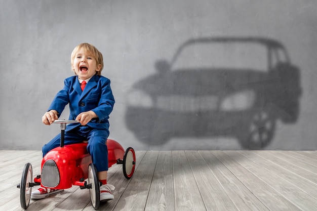 Gelukkig kind wil racen. Grappige jongen droomt van een auto.