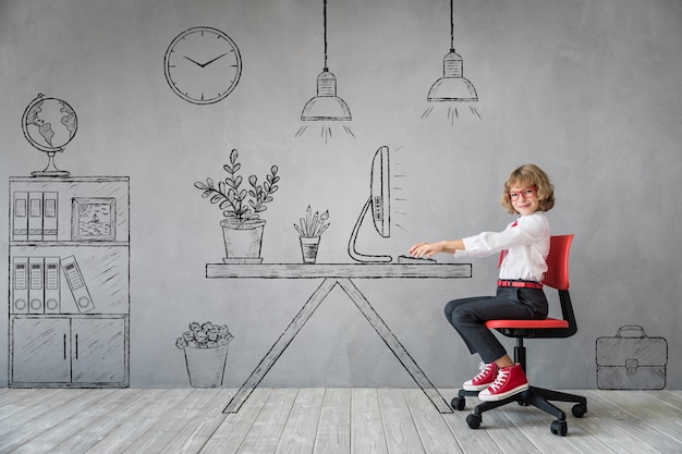 Gelukkig kind zit aan het bureau in denkbeeldig kantoor