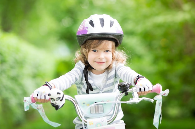 Gelukkig kind zittend op de fiets buiten in het voorjaarspark