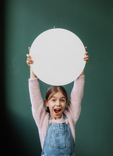 Gelukkig kindmeisje dat een witte schone cirkel houdt voor een inschrijving