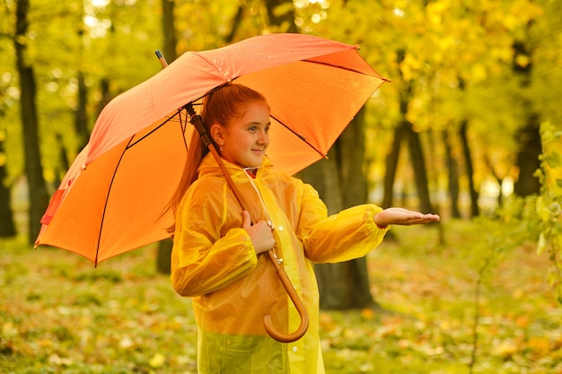 Gelukkig kindmeisje met een paraplu en rubberen laarzen op een herfstwandeling