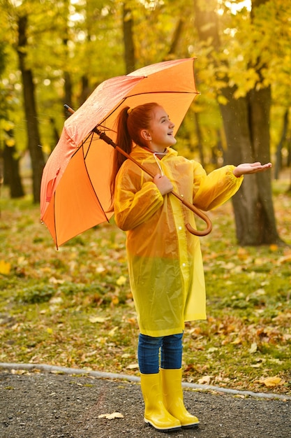 Gelukkig kindmeisje met een paraplu en rubberen laarzen op een herfstwandeling