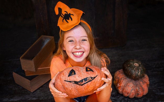 Gelukkig kindmeisje met pompoen Jack op donker hout