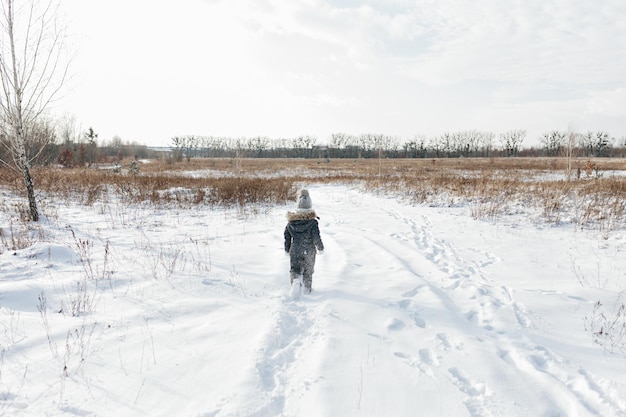 Gelukkig kindmeisje op een besneeuwde winterwandeling Koele zwarte sneeuwoverall dragen Winteroutfit