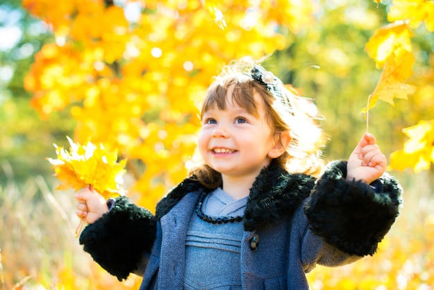 Gelukkig klein kind, babymeisje lachen en spelen in de herfst op de natuurwandeling buiten.