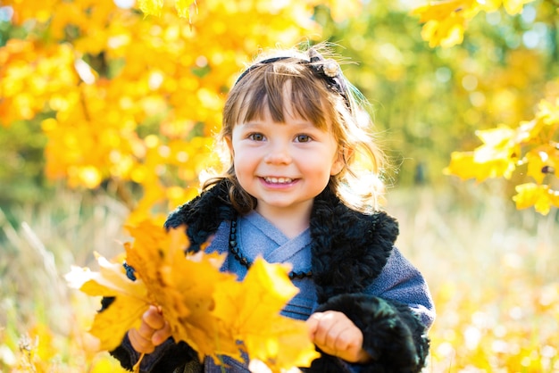 Gelukkig klein kind, babymeisje lachen en spelen in de herfst op de natuurwandeling buiten.