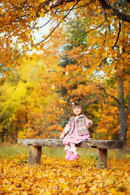 Gelukkig klein kind, babymeisje lachen en spelen in de herfst op de natuurwandeling buiten.