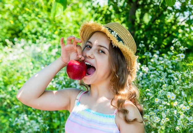 Gelukkig klein meisje bijt rijp rood appelfruit in de zomertuin op zonnige buiten vitamine