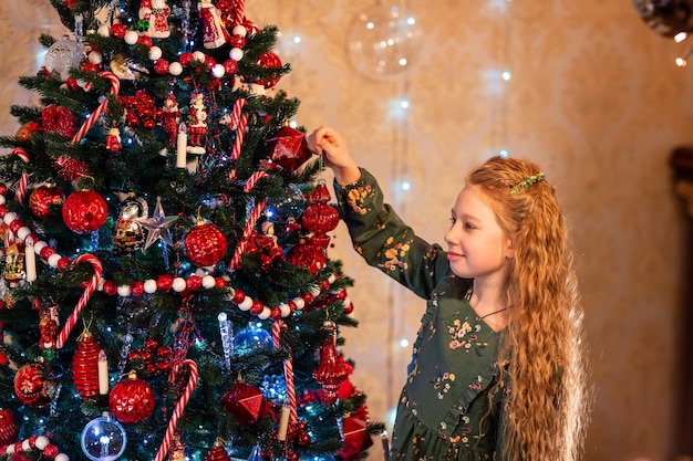 Gelukkig klein meisje dat de kerstboom versiert op kerstavond