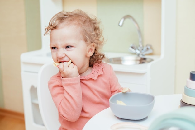 Gelukkig klein meisje dat pasta eet in de kleuterschool