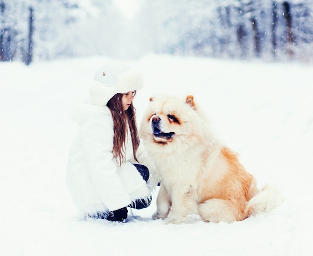 Gelukkig klein meisje en hond chow chow in winter park