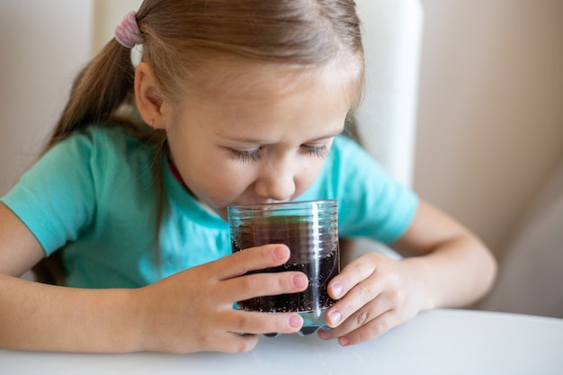 Gelukkig klein meisje frisdrank drinken uit glas