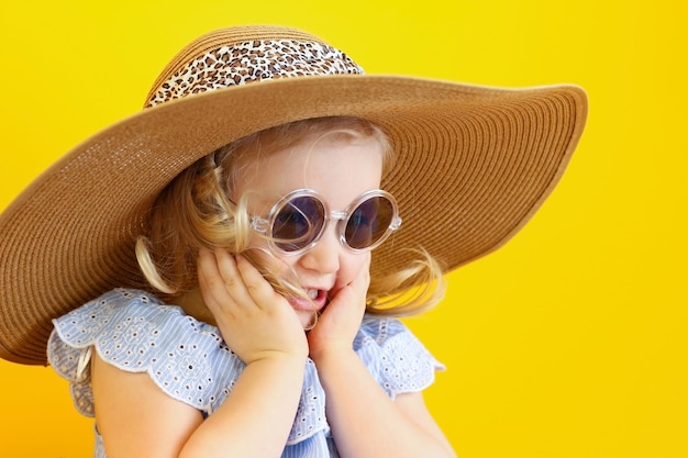 Gelukkig klein meisje het kind geniet van de zomer Binnenkort op vakantie en ze is aan het inpakken voor een reis Hij probeert een zonnebril op een hoed en drinkt sap