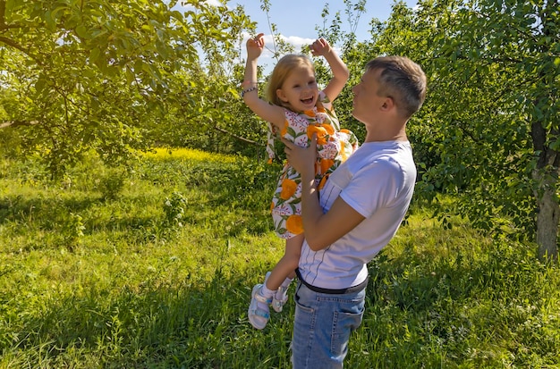 Gelukkig klein meisje in de armen van haar vader Dochter speelt en lacht in de natuur Vaderdag vader met vrolijke lachende dochter in zijn armen tussen de bomen in de natuur die met haar speelt