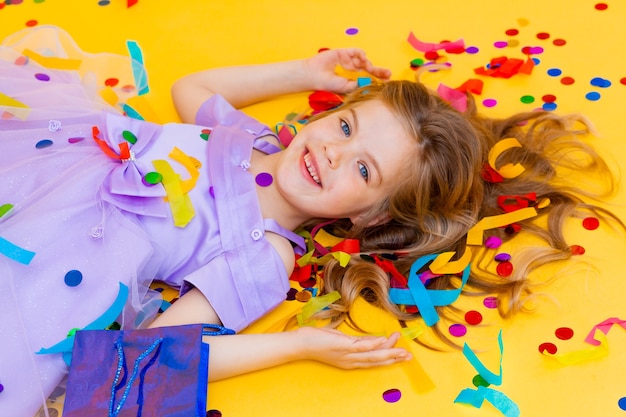 Gelukkig klein meisje in een blauwe jurk viert een feest met confetti bovenaanzicht. Verjaardagskind, positieve emoties.