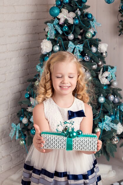 Gelukkig klein meisje in jurk met hebben een kerstcadeau