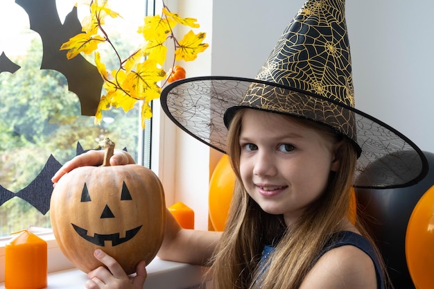 Gelukkig klein meisje in kostuum met pompoen die plezier heeft op Halloween-feest