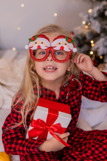 gelukkig klein meisje in pyjama thuis verheugt zich en pakt cadeautjes uit voor Kerstmis. Hoge kwaliteit foto