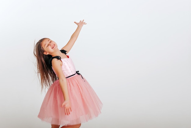 Gelukkig klein meisje in roze jurk met plezier op een witte achtergrond Ruimte voor tekst