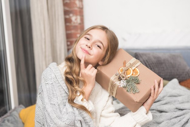 Foto gelukkig klein meisje met cadeau in handen dromen