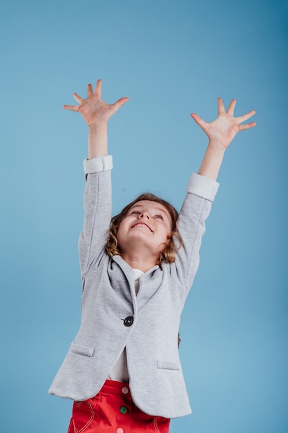 Gelukkig klein meisje met haar handen aan de orde gesteld genietend van de overwinning geïsoleerd op een blauwe achtergrond