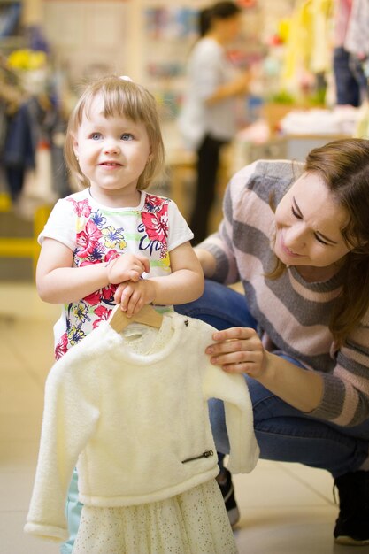 Gelukkig klein meisje met haar moeder die kleding kiest