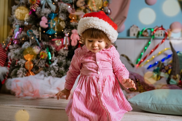 Gelukkig klein meisje op de achtergrond van de kerstboom die speelt
