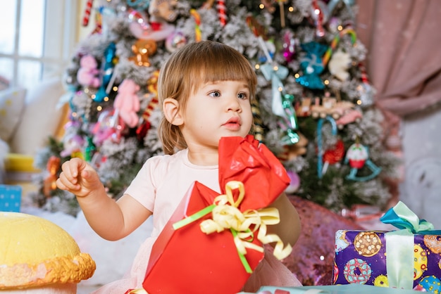 Gelukkig klein meisje op de achtergrond van de kerstboom die speelt