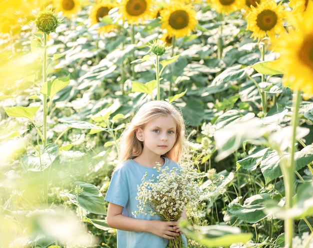 Gelukkig klein meisje op het gebied van zonnebloemen in de zomer.