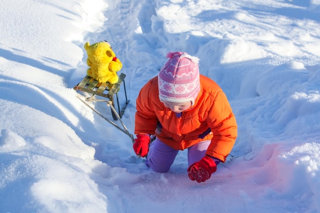 Gelukkig klein meisje speelt met haar berenspeelgoed in het besneeuwde sneeuwpark