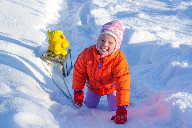 Gelukkig klein meisje speelt met haar berenspeelgoed in het besneeuwde sneeuwpark