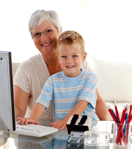 Gelukkig kleinzoon met behulp van een computer met zijn grootmoeder