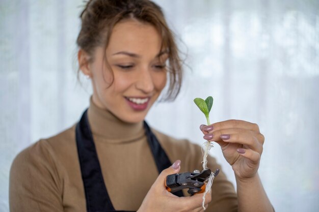 Gelukkig lachend aantrekkelijke vrouw wortels van bloem spruiten trimmen voor het planten