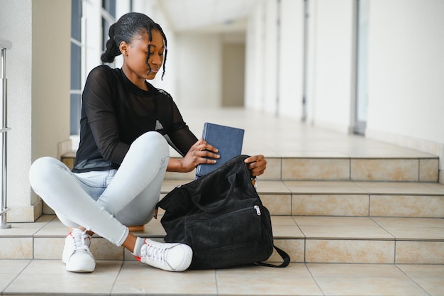 Gelukkig lachend afro-amerikaans student meisje met rugzak op universitaire achtergrond technologie onderwijs vrije tijd concept