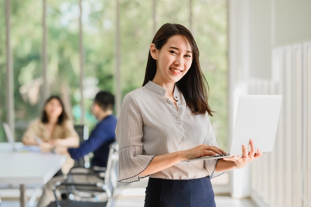 Gelukkig lachend aziatische vrouw met laptop notebook met collega