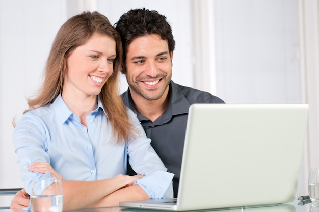 Gelukkig lachend jong koppel kijken samen op computer laptop