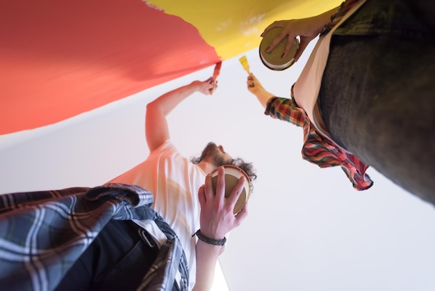 gelukkig lachend jong koppel schilderen binnenmuur van nieuw huis