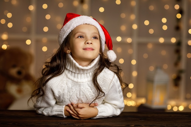 Gelukkig lachend kind meisje in kerstmuts dromen over de vakantie