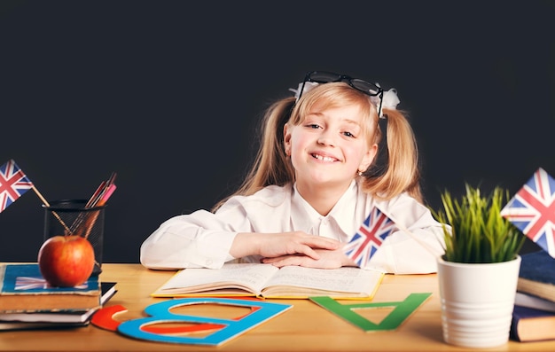 Gelukkig lachend meisje dat Engelse taal leert met boek voor donkere achtergrond