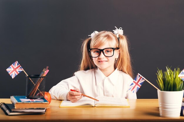 Gelukkig lachend meisje draagt een slimme bril die Engels leert met een boek voor een donkere achtergrond