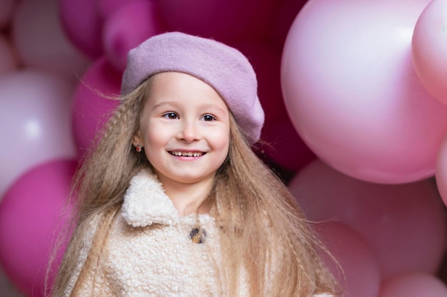 Gelukkig lachend meisje in baret spelen met roze ballonnen. kind op vakantie. verjaardagsfeestje voor kinderen