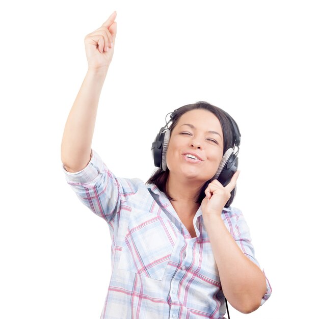 Gelukkig lachend mooie jonge vrouw luisteren muziek met koptelefoon en zingen op een witte achtergrond